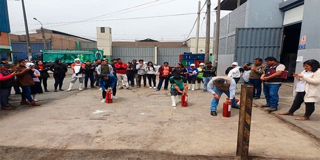 Práctica de uso de extintores con trabajadores en el patio de una empresa